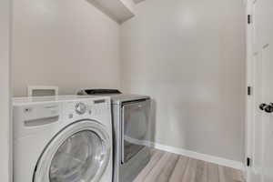 Washroom with wood finished floors and washer and dryer