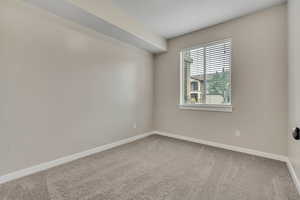 Spare room featuring light colored carpet and baseboards