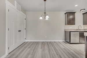 Unfurnished dining area with a chandelier, light wood-style floors, and recessed lighting