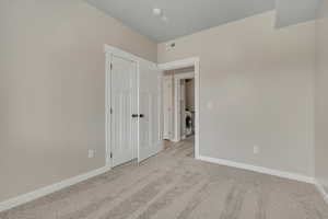 Unfurnished bedroom with carpet, independent washer and dryer, and a closet