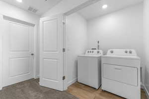 Laundry area featuring recessed lighting, washer and dryer, and light wood-style floors