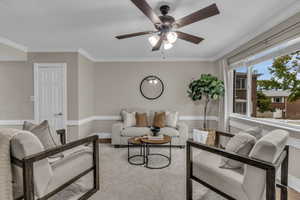 Living room featuring ornamental molding, a ceiling fan, and wood finished floors