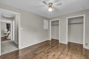 Unfurnished bedroom featuring multiple closets, dark wood-type flooring, and a ceiling fan