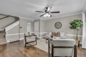 Living area with dark wood-type flooring, stairs, crown molding, and a ceiling fan