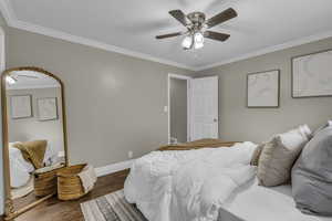 Bedroom with ornamental molding, dark wood finished floors, and ceiling fan