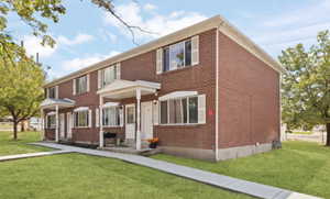 Colonial-style house featuring a front lawn, brick siding, and a porch