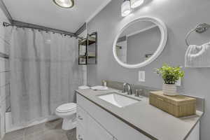 Bathroom with shower / tub combo, vanity, a textured ceiling, ornamental molding, and light tile patterned floors
