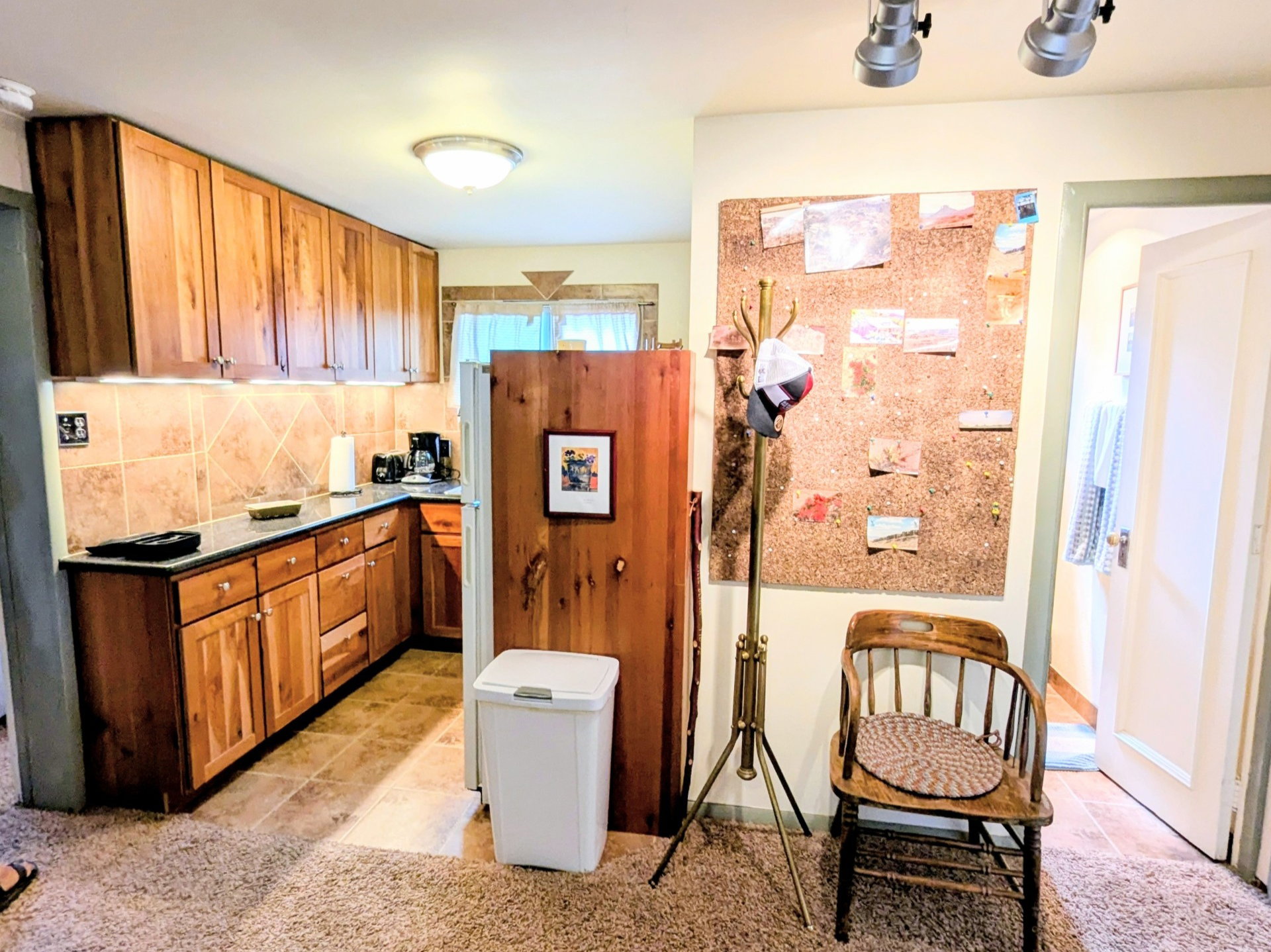 Kitchen with light tile patterned floors, brown cabinets, backsplash, light carpet, and rail lighting