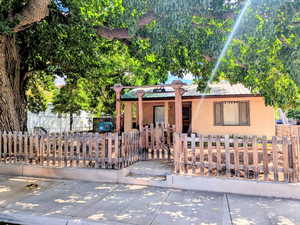 View of front of home with stucco siding, a metal roof, a fenced front yard, and a gate