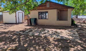 Back of property with stucco siding and a storage shed