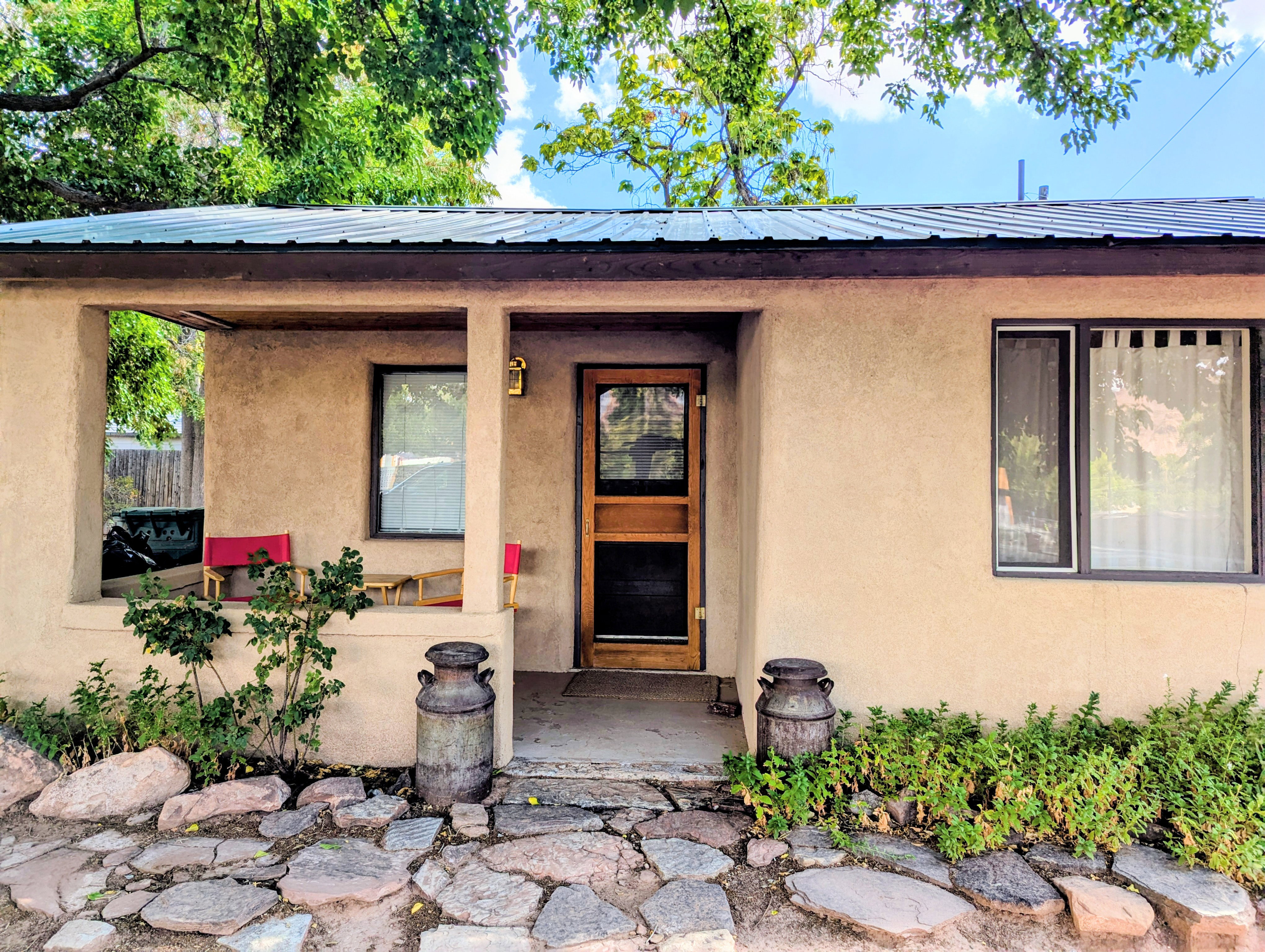 Entrance to property with a metal roof, stucco siding, and covered porch
