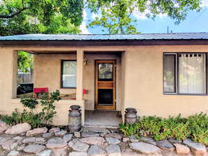 Entrance to property with a metal roof, stucco siding, and covered porch