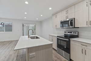 Kitchen with light brown cabinetry, appliances with stainless steel finishes, light wood finished floors, and recessed lighting