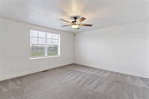 Spare room featuring light carpet, a textured ceiling, and ceiling fan