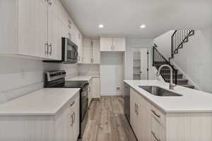Kitchen featuring appliances with stainless steel finishes, light wood-type flooring, recessed lighting, an island with sink, and light stone countertops