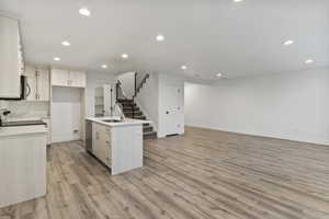 Kitchen featuring recessed lighting, a kitchen island with sink, light wood finished floors, open floor plan, and appliances with stainless steel finishes