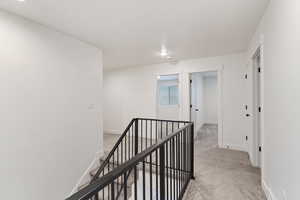 Hall with an upstairs landing and light colored carpet