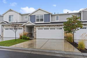 View of front of home featuring stone siding, driveway, a garage, and board and batten siding