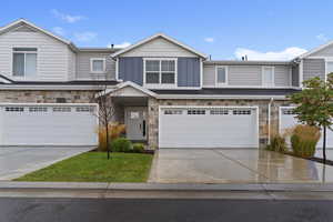 View of front of house featuring stone siding, driveway, board and batten siding, and an attached garage