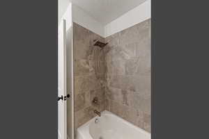 Full bath with shower / washtub combination and a textured ceiling