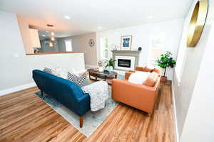 Living area with a glass covered fireplace, wood finished floors, and recessed lighting