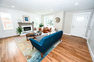 Living room with light wood-style flooring, a fireplace, and recessed lighting