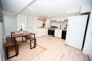 Kitchen with white cabinets, freestanding refrigerator, stainless steel electric range oven, backsplash, and a textured ceiling