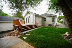 Back of house featuring board and batten siding, a wooden deck, brick siding, and roof with shingles