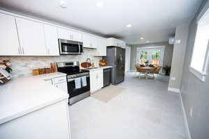 Kitchen with appliances with stainless steel finishes, tasteful backsplash, recessed lighting, white cabinets, and light tile patterned floors
