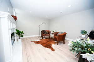 Living area featuring light wood-type flooring, a high end fireplace, recessed lighting, and a textured ceiling