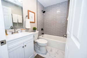 Full bath featuring  shower combination, vanity, and light marble finish flooring