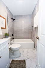 Full bathroom with shower / bath combination, vanity, and light marble finish floors