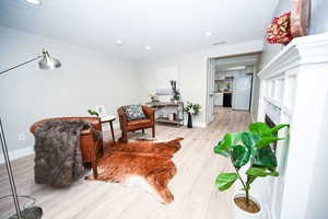 Living area with light wood-type flooring, a fireplace, recessed lighting, and a textured ceiling
