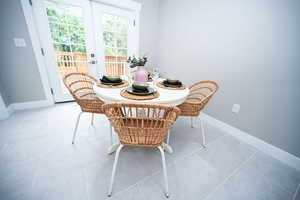 Dining space with light tile patterned flooring and french doors