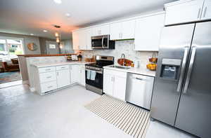 Kitchen with appliances with stainless steel finishes, white cabinets, light countertops, and recessed lighting