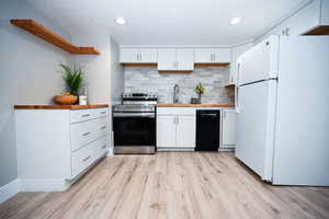 Kitchen featuring white cabinetry, freestanding refrigerator, open shelves, decorative backsplash, and recessed lighting