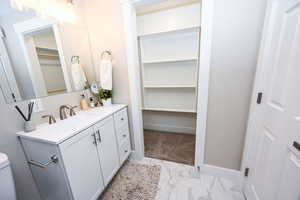 Bathroom with vanity, light marble finish flooring, and a walk in closet