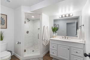 Bathroom with a marble finish shower, vanity, dark wood-type flooring, and a textured ceiling