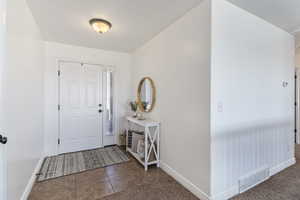 Foyer entrance featuring dark tile patterned flooring and baseboards