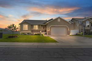 View of front of property featuring stucco siding, a garage, concrete driveway, and brick siding