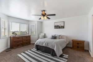 Carpeted bedroom with baseboards and a ceiling fan