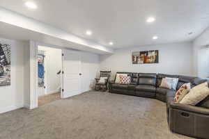 Carpeted living area with recessed lighting and baseboards