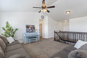 Living room featuring lofted ceiling, carpet flooring, and ceiling fan