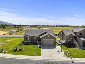 View of front facade featuring an attached garage, concrete driveway, roof with shingles, and stucco siding