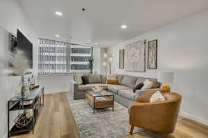 Living area with light wood-type flooring and recessed lighting