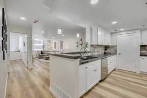 Kitchen with open floor plan, white cabinets, decorative backsplash, hanging light fixtures, and recessed lighting