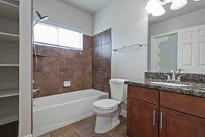 Bathroom featuring vanity, shower / tub combination, and dark tile patterned floors