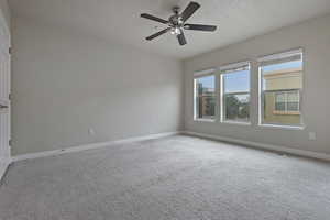 Unfurnished room with carpet, ceiling fan, and a textured ceiling