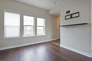 Empty room with baseboards and dark wood-style flooring