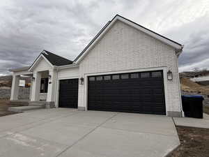 View of property exterior featuring brick siding, concrete driveway, and a garage